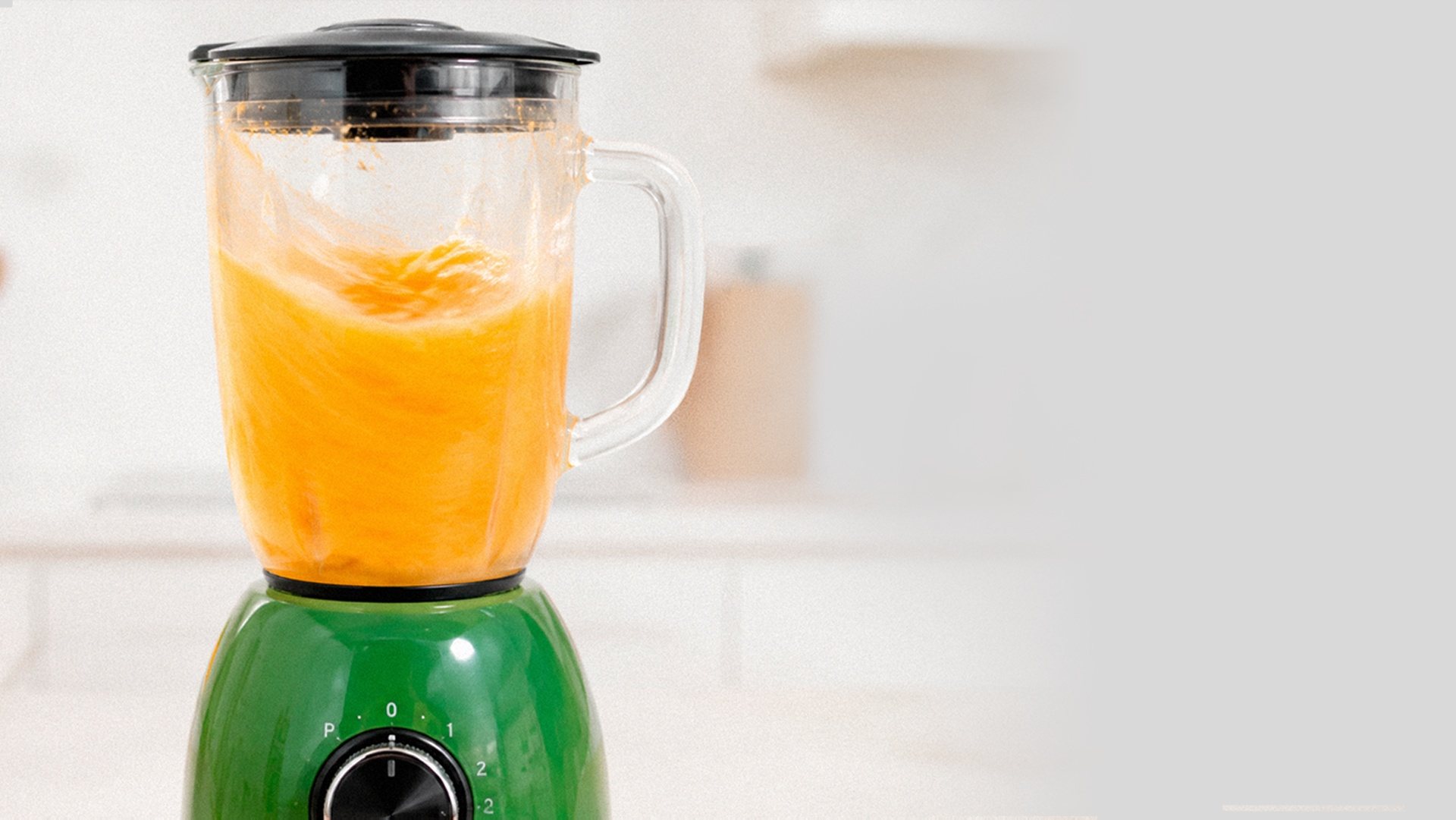 Liquidificador com vitamina de laranja numa cozinha clara